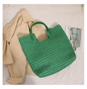 Close-up of green woven straw tote bag with smooth faux leather handles for beach vacation