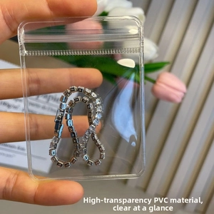 Hand holding transparent PVC jewelry bag with silver tennis bracelet inside