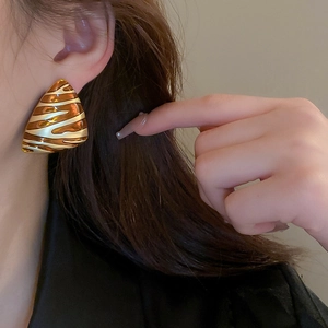 Gros plan de boucles d'oreilles triangulaires dorées avec motifs vagues zébrées bruns