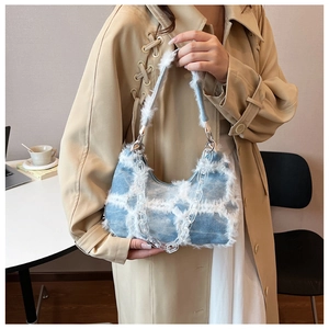 Detail of light blue denim handbag with white plush trim and transparent chain strap
