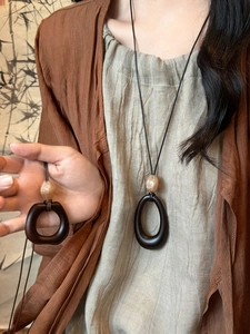 Detail of vintage geometric wood resin pendant necklace on minimalist black cord