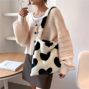 Close-up of fluffy black and white heart pattern tote bag worn over a shoulder