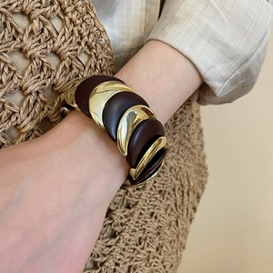 Close-up of a gold and brown layered chunky moon-inspired bangle on a female wrist