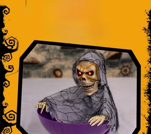 Close-up of animated Halloween skull prop with glowing eyes and tattered grey cloak decor