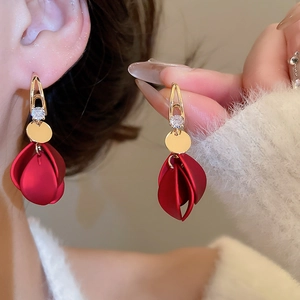 Macro shot of elegant red petal tassel earrings with zircon studs worn by a model