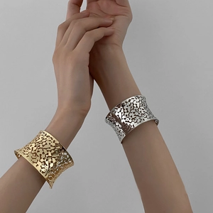 Detail of wide open cuff bracelet with irregular organic hollow texture in gold and silver