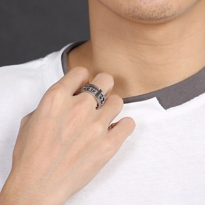 Détail de la bague en acier inoxydable argenté avec gravure de croix vintage portée au doigt