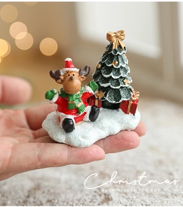Figurines de Noël miniatures en résine montrant un renne et un sapin en main