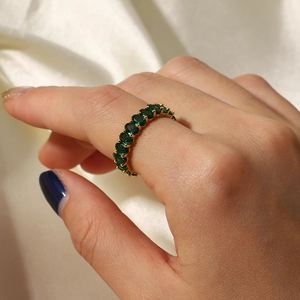 Close-up of a gold ring featuring an oval green gemstone worn on a finger