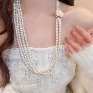 Close-up of multi-layer pearl necklace with a diamond-encrusted champagne gold flower clasp