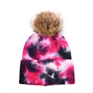 Détail du bonnet en tricot tie-dye avec pompon en fausse fourrure et revers