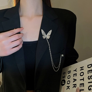Silver butterfly brooch with zircon wings and pearl chain worn on a black suit blazer