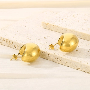 Macro shot of 18K gold plated teardrop hollow earrings on a stone textured surface
