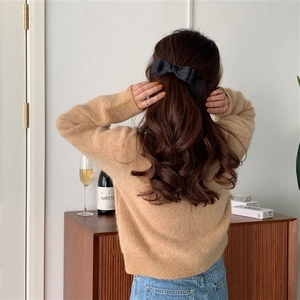 Rear view of model wearing a black bow hair clip for half-up hair styling accessory
