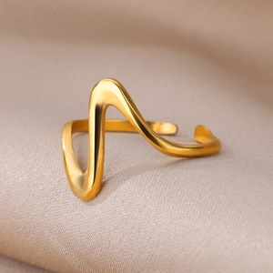 Macro detail of wave shaped gold ring on silk background showcasing polished metal texture