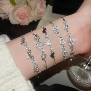 Close-up of five silver-tone bracelets with butterfly and flower charms on a model's wrist