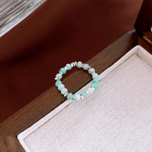 Macro shot of Amazonite beaded ring with silver spacers resting on a wooden box