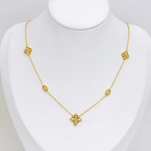Elegant gold clover necklace with zircons on white display stand with smooth lighting
