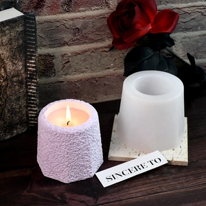 Octagonal silicone candle mold with finished purple textured wax candle on wood table