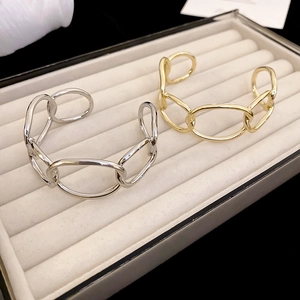 Detail shot of chunky gold and silver chain link bangles on white velvet display tray