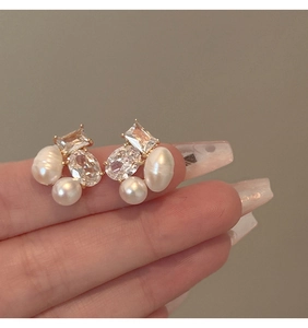 Detail of golden earrings with zircon and freshwater pearls showing elegant texture