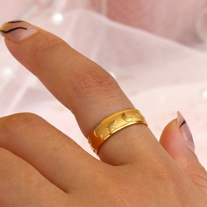 Close-up of golden ring with star and moon relief motifs worn on a finger