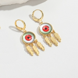 Detailed close-up of golden Evil Eye tassel earrings with three delicate feather pendants