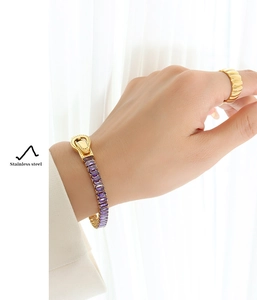 Detail of gold plated stainless steel bracelet with purple baguette cut stones and magnetic clasp