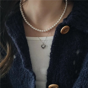 Detail of layered 925 silver necklace set with heart pendant and white pearls