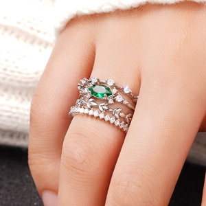 Detalle del juego de cuatro anillos plateados con piedra marquesa verde esmeralda y circonio