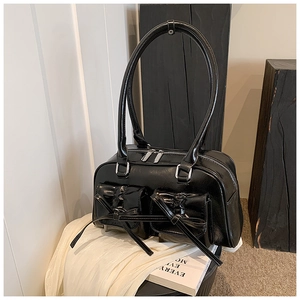 Close-up of black glossy handbag featuring decorative bow pockets and round handles