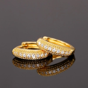 Close-up of golden hoop earrings with sparkling cubic zirconia on black reflective background