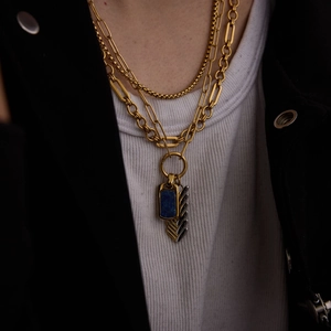 Detail of layered gold titanium necklace featuring lapis lazuli and arrow feather charms