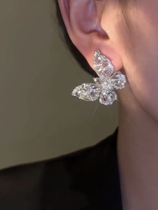 Close-up of a model wearing sparkling zircon butterfly stud earrings in silver