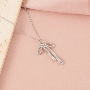 Vue détaillée d'un collier nœud argenté sur tissu rose avec un élément en pierre beige