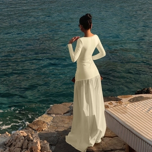 Back view of long sleeve ivory beach maxi dress with a flowing A-line skirt by the ocean