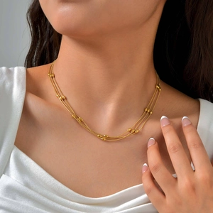 Close-up of three-layer gold beaded snake chain necklace worn on neck and collarbone