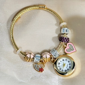 Detail of golden charm bracelet watch with pink floral beads and rhinestone heart pendant
