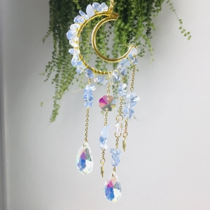 Detail of golden crescent moon suncatcher with blue crushed crystals and star pendants