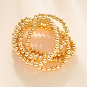 Detailed close-up of golden beaded stretch bracelets set with glossy metallic finish