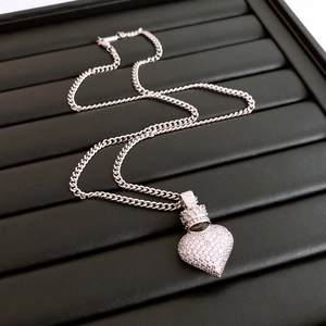 Macro view of silver heart pendant with crown detail and cubic zirconia on Cuban chain