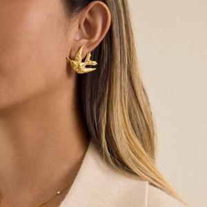 Boucles d'oreilles hirondelle en or élégantes avec détails fins portées par un mannequin