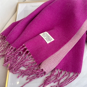Detail view of double-sided magenta imitation cashmere scarf with fringe and brand label