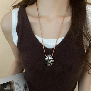 Detail of vintage silver shell pendant necklace with brown cord on a model