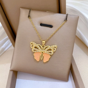 Macro view of golden butterfly pendant with clear crystals and pink enamel detail