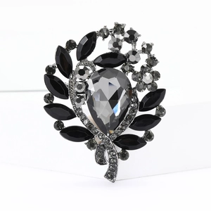 Detailed close-up of leaf and flower brooch with black rhinestones and silver metal