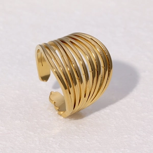 Bague ouverte multicouche en acier inoxydable doré posée sur une pierre blanche