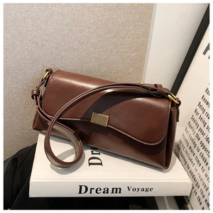 Detailansicht der braunen Leder-Schultertasche mit goldener Schnalle auf einem Buch