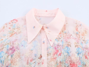Detail of floral embroidery and pink chiffon lapel collar with white buttons