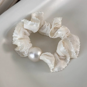 Detailed view of cream lace hair scrunchie featuring a large glossy decorative pearl